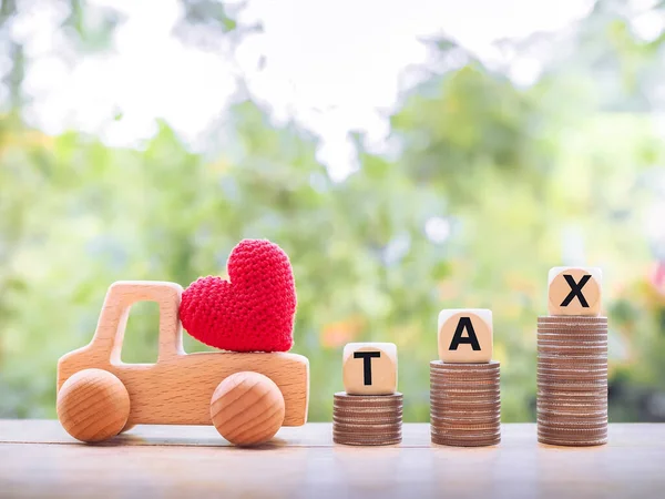 Red heart on wooden toy car, Wooden blocks with the word TAX on stack of coins. The concept of paying tax for car. Car taxes.