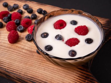 Ahşap bir masada doğal Yunan yoğurt ve yabani çilek bir bardak, üst görünümü, makro çekim