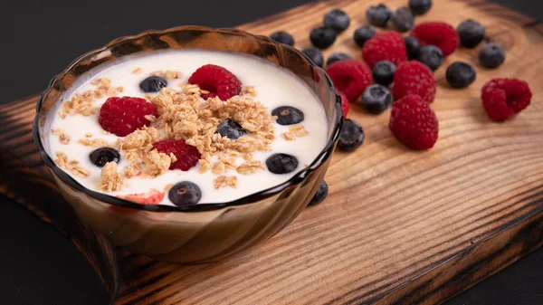 One glass of natural Greek yogurt and wild berries on a wooden table, top view, macro shot