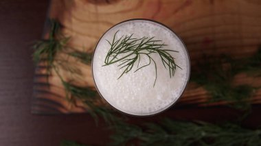 Türk ya da Azerbaycan geleneksel Ayran içeceği ya da otlu Kefir ve ahşap masa manzaralı bir bardakta dereotu. Diyet için mayalanmış süt içeceği. Uzayı kopyala Sağlıklı beslenme kavramı.