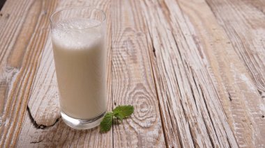 Türk ya da Azerbaycan geleneksel Ayran içeceği ya da otlu Kefir ve ahşap masa manzaralı bir bardakta dereotu. Diyet için mayalanmış süt içeceği. Uzayı kopyala Sağlıklı beslenme kavramı.