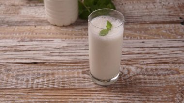 Türk ya da Azerbaycan geleneksel Ayran içeceği ya da otlu Kefir ve ahşap masa manzaralı bir bardakta dereotu. Diyet için mayalanmış süt içeceği. Uzayı kopyala Sağlıklı beslenme kavramı.