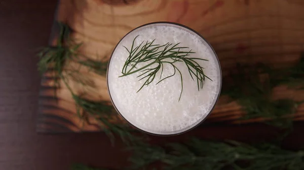 Türk ya da Azerbaycan geleneksel Ayran içeceği ya da otlu Kefir ve ahşap masa manzaralı bir bardakta dereotu. Diyet için mayalanmış süt içeceği. Uzayı kopyala Sağlıklı beslenme kavramı.