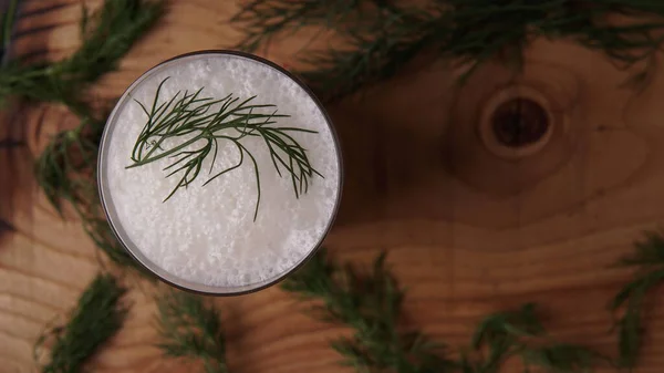 Türk ya da Azerbaycan geleneksel Ayran içeceği ya da otlu Kefir ve ahşap masa manzaralı bir bardakta dereotu. Diyet için mayalanmış süt içeceği. Uzayı kopyala Sağlıklı beslenme kavramı.