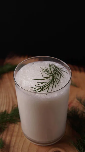 Türk ya da Azerbaycan geleneksel Ayran İçeceği ya da Kefir derebeyliği, siyah arka planda, tahta bir masada bir bardakta. Diyet için mayalanmış süt içeceği. Uzayı kopyala Sağlıklı beslenme kavramı.