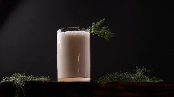 Türk ya da Azerbaycan geleneksel Ayran İçeceği ya da Kefir derebeyliği, siyah arka planda, tahta bir masada bir bardakta. Diyet için mayalanmış süt içeceği. Uzayı kopyala Sağlıklı beslenme kavramı.