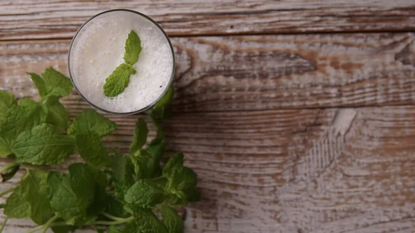 Türk ya da Azerbaycan geleneksel Ayran içeceği ya da otlu Kefir ve ahşap masa manzaralı bir bardakta dereotu. Diyet için mayalanmış süt içeceği. Uzayı kopyala Sağlıklı beslenme kavramı.