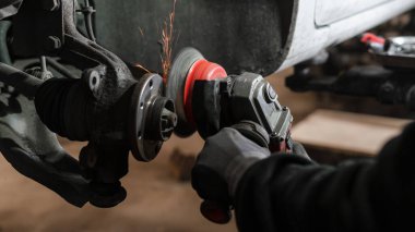 Benzin istasyonundaki bir oto tamircisi, yolcu vagonu için fren disklerini ve fren pedlerini yenileriyle değiştiriyor..