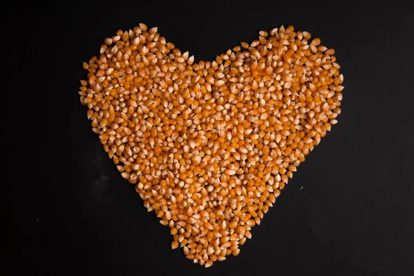 stock image heart of corn kernels on a black background top view