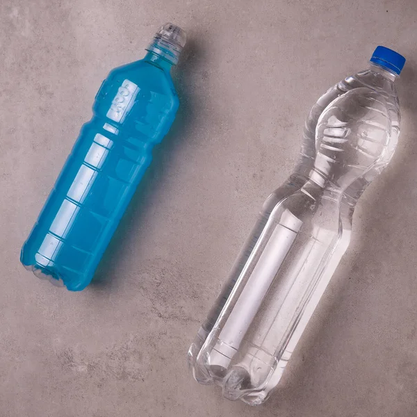 blue isotonic to replenish electrolytes and energy in a plastic bottle on a concrete background next to a of bottle water