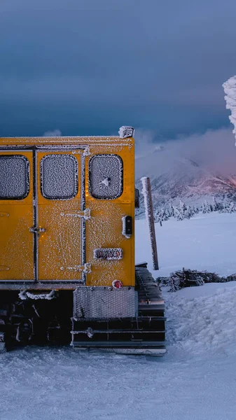 snow-covered atmospheric mountain with black clouds illuminated by the setting sun. vertical wallpaper for smartphone.