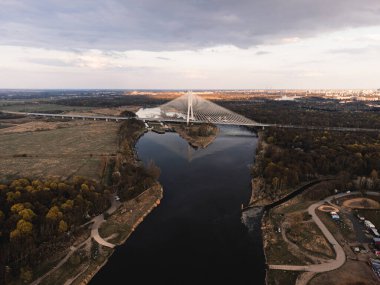 a large white suspension bridge over the river on which cars drive in Wroclaw, Poland, shot from a drone