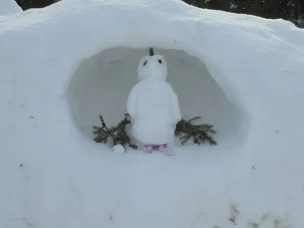 阳光明媚的日子里 一个用云杉枝条装饰的又小又可爱的雪人在一个圆孔里挖了一大堆白雪 — 图库照片
