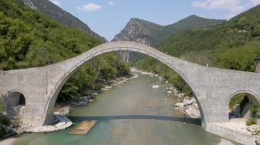 Nehir, Dağlar ve Antik Taş Köprüsü 'nün güzel hava görüntüleri. Suya yüzen, kano yapan ve spor yapan insanlar.