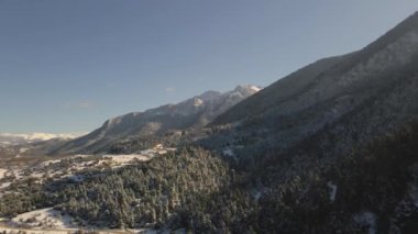 Karla dolu bir dağın insansız hava aracı görüntüsü. Dağlar, ağaçlar, kış.