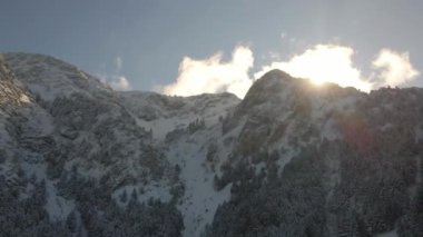 Karla dolu bir dağın insansız hava aracı görüntüsü. Dağlar, ağaçlar, kış.