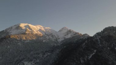 Karla dolu bir dağın insansız hava aracı görüntüsü. Dağlar, ağaçlar, kış.
