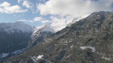 Karla dolu bir dağın insansız hava aracı görüntüsü. Dağlar, ağaçlar, kış.