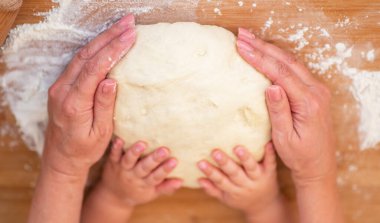 Büyükannem ve torunum hamuru şekillendirmek için kurabiye bıçağı kullanıyorlar. Noel için kurabiye hazırlayan küçük tatlı kız ve büyük anne. Yaşlı nineyle mutfakta yemek pişiren torun..