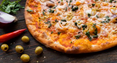 Tahta masada pizza var. Restoran ve pizzacılar için konsept promosyon şablonu. Yemek malzemeleri ve baharatlı geleneksel İtalyan pizzası. Uzayı kopyala Üst Manzara. Pankart. Pizza menüsü.