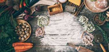 Kırsal arka planda makarna yapmak için gerekli malzemeler, üst manzara. Düz yatıyordu. İtalyan tarifi. El yapımı. Çiğ makarna yapma süreci. Taze İtalyan makarnası üretiyorum..
