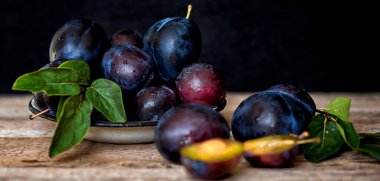 Köy arka planında yeşil yapraklı olgun erik. Olgun taze organik erikler..