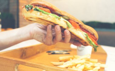 Barbecue grilled hot dog with ketchup and yellow mustard and cup of coffee. Classic american hot dog in craft paper. Closeup in man hands. Street food, fast food.
