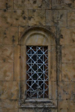 Taş kale duvarının arka planı. Pencereli eski kahverengi duvar. Duvar dokusu. Eski ortaçağ duvarındaki taş bloklar. Grafiksel doku ögesi.