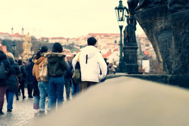 Foggy day on Charles Bridge, Prague, Czech Republic. Walking people, statues and Old Town towers. Romantic travel destination. Vintage filter of image.