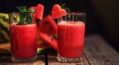 Kırsal ahşap arka planda karpuz. Sulu, olgun, kırmızı karpuz dilimleri. Taze meyve suyu. Kokteyl ve meşrubat. Tazeleyici yaz içeceği.