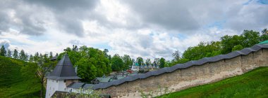 View of beautiful buildings and orthodox churches ancient Pskov-Pechersky monastery. Fortress wall and tower. Pechory, Pskov, Russia.
