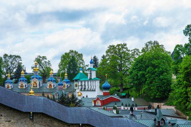 View of beautiful buildings and orthodox churches ancient Pskov-Pechersky monastery. Fortress wall and tower. Pechory, Pskov, Russia.