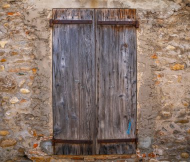 Vintage old wooden shutters on the stone wall background. Wooden brown window frame. Window with shutters in the house close-up.