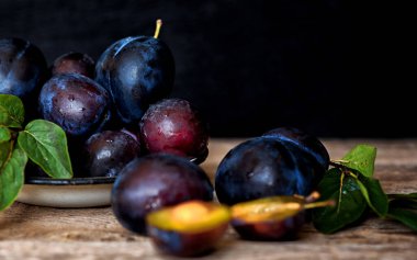 Köy arka planında yeşil yapraklı olgun erik. Olgun taze organik erikler..
