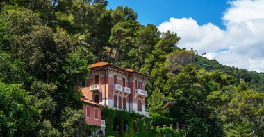 Akdeniz 'in Liguria kıyı şeridinin sabah manzarası. Büyüleyici botanik bahçesinde Akdeniz bitkileriyle lüks bir villa. İtalya, Avrupa. Bulutlu mavi gökyüzü güneşli gün cennet manzarası.