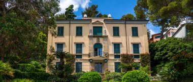 Akdeniz 'in Liguria kıyı şeridinin sabah manzarası. Büyüleyici botanik bahçesinde Akdeniz bitkileriyle lüks bir villa. İtalya, Avrupa. Bulutlu mavi gökyüzü güneşli gün cennet manzarası.