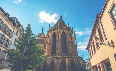 Renkli çiçekler ve Colmar 'daki geleneksel yarı ahşap evler vasıtasıyla Aziz Martin kilisesinin bulanık görüntüsü. Güneşli bir günde sevimli eski bir kasaba. Fransa, Alsace.