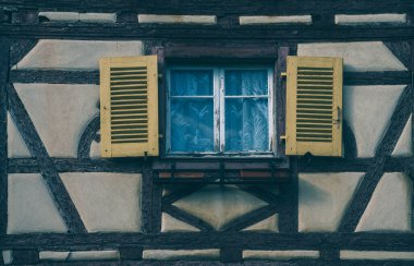 Pencereleri ve koyu keresteleri olan eski bir ev duvarı. Tarihi, renkli şehir Colmar, Fransa, Alsace 'de tarihi ahşap panjurlu geleneksel yarı ahşap evlerin önü..