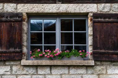 Penceresi olan eski bir retro evin eski taş duvarı. Panjurlu ahşap pencere ve eski evin duvarında antik camlar, klasik bina. Tonu ayarlanmış resim.