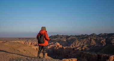 Sırt çantalı kadın yürüyüşçü manzaranın keyfini çıkarıyor. Kanyon boyunca seyahat et. Dağ geçidi. Sonbaharda dağ manzarası. Kanyonun üzerindeki mavi gökyüzü. Gürültü ve tahılla klasik ton filtre efekti.