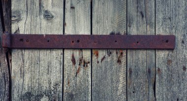 Çelik menteşeli eski, yıpranmış ahşap kapı. Sorunlu paneller. Eski duvar dokusu arka planı. Paslı kapı mandalı olan eski ahşap kapının ayrıntıları..