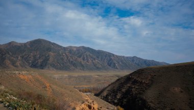 Bulutlu gökyüzü ile inanılmaz bir dağ manzarası. Güzel kırsal kesimin manzarası. Dağlarda harika bir sonbahar. Kuru çayır ve yuvarlanan tepeler. Gürültü ve tahılla klasik ton filtre efekti.