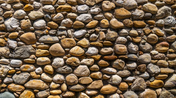 Vintage stone wall. Old castle wall texture as a background or texture. Decorative uneven cracked real stone wall surface.