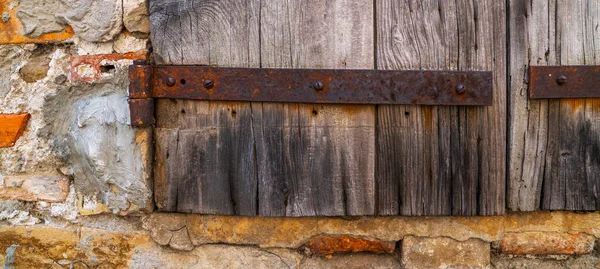 钢制铰链的部分风化木门 沮丧的木板板 城堡石墙纹理背景 带有油漆残留物和生锈门闩的旧木门的细节 — 图库照片