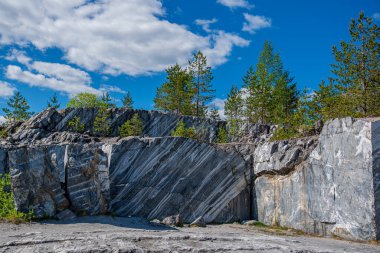 Terk edilmiş eski bir taş ocağında büyük gri taşlar. Mermer dokusu. Kayalıklarda pürüzsüz kesikler. Mermer ocağı yatay. Doğal taş. Mermer ocağı, vahşi mermer kayalar..
