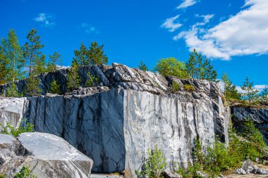 Terk edilmiş eski bir taş ocağında büyük gri taşlar. Mermer dokusu. Kayalıklarda pürüzsüz kesikler. Mermer ocağı yatay. Doğal taş. Mermer ocağı, vahşi mermer kayalar..