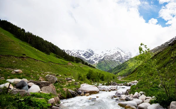 风景如画的山水 背景是一条小河和一条高加索山脊 春天的一天 绿油油的草地 白雪覆盖的山峰 — 图库照片