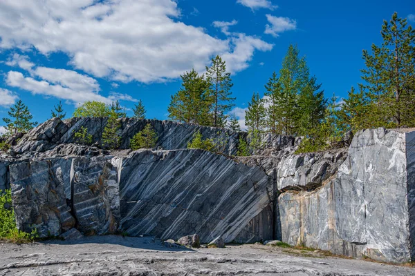 Terk edilmiş eski bir taş ocağında büyük gri taşlar. Mermer dokusu. Kayalıklarda pürüzsüz kesikler. Mermer ocağı yatay. Doğal taş. Mermer ocağı, vahşi mermer kayalar..