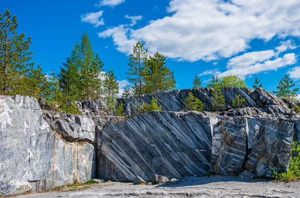 Terk edilmiş eski bir taş ocağında büyük gri taşlar. Mermer dokusu. Kayalıklarda pürüzsüz kesikler. Mermer ocağı yatay. Doğal taş. Mermer ocağı, vahşi mermer kayalar..