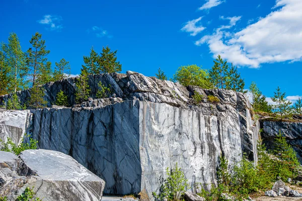 Terk edilmiş eski bir taş ocağında büyük gri taşlar. Mermer dokusu. Kayalıklarda pürüzsüz kesikler. Mermer ocağı yatay. Doğal taş. Mermer ocağı, vahşi mermer kayalar..